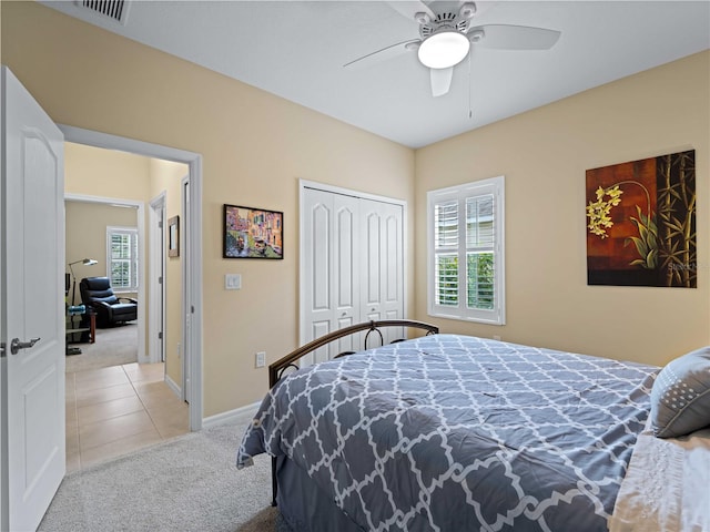 bedroom featuring ceiling fan, light carpet, and a closet