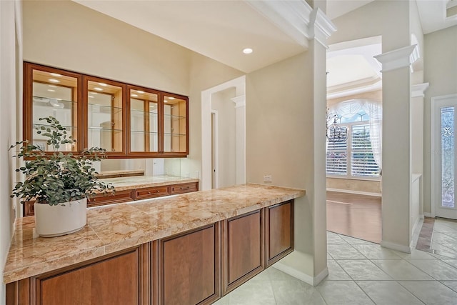 bar with decorative columns, light stone countertops, and light tile patterned floors