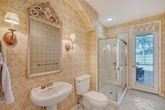 bathroom with a shower with door, sink, tile walls, tile patterned flooring, and toilet