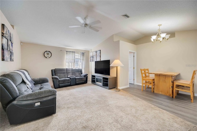 living room featuring wood-type flooring, a textured ceiling, ceiling fan with notable chandelier, and vaulted ceiling