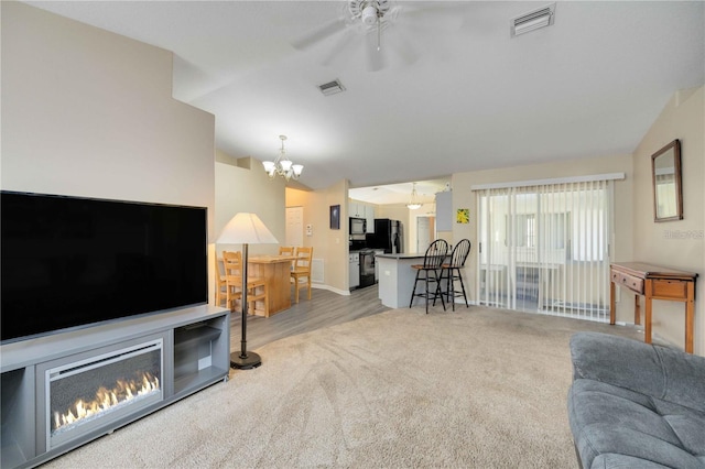 living room featuring ceiling fan with notable chandelier, lofted ceiling, and light colored carpet