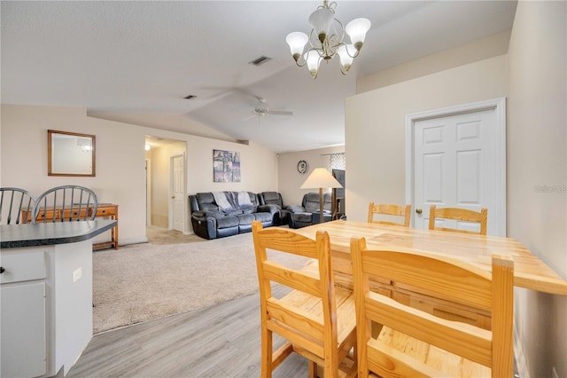 dining space featuring ceiling fan with notable chandelier, light wood-type flooring, and lofted ceiling