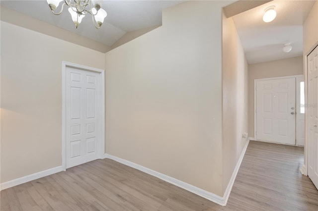 interior space featuring light hardwood / wood-style flooring, lofted ceiling, and a notable chandelier