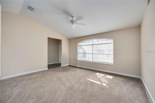 carpeted empty room with vaulted ceiling, ceiling fan, and a textured ceiling