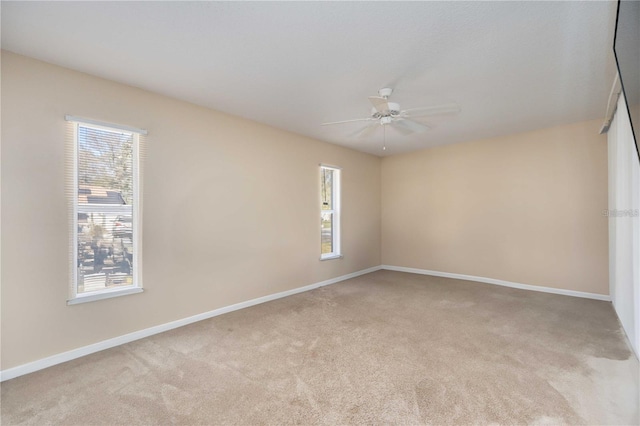 carpeted spare room with ceiling fan and plenty of natural light