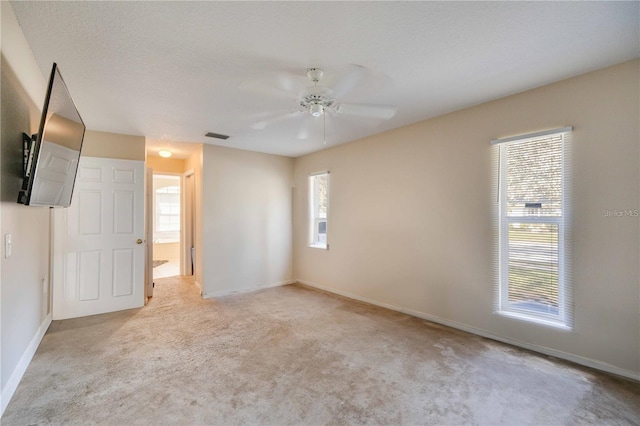 carpeted spare room featuring ceiling fan and a textured ceiling