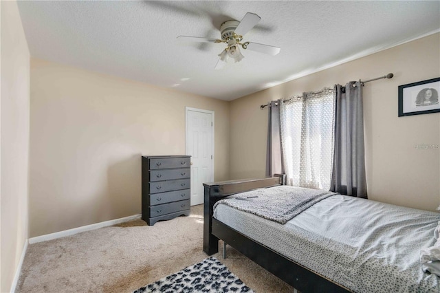 bedroom with ceiling fan, light colored carpet, and a textured ceiling