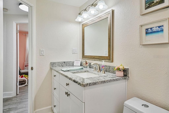 bathroom with vanity, toilet, and hardwood / wood-style floors