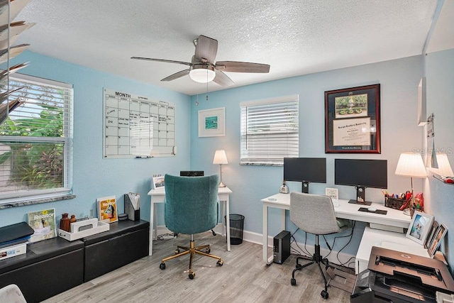 home office with ceiling fan, light hardwood / wood-style floors, and a textured ceiling