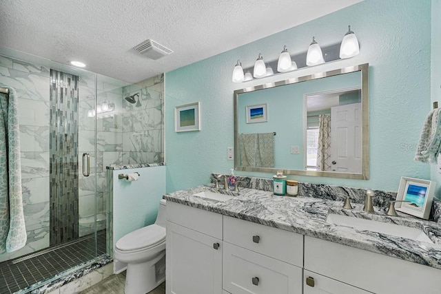 bathroom with vanity, toilet, a textured ceiling, and walk in shower