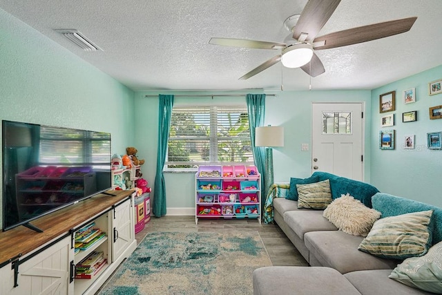 living room featuring ceiling fan, a textured ceiling, and light hardwood / wood-style floors