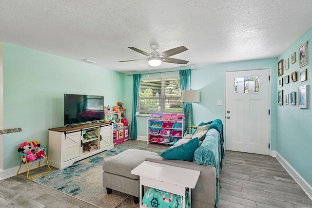 living room featuring ceiling fan, a textured ceiling, and light hardwood / wood-style flooring