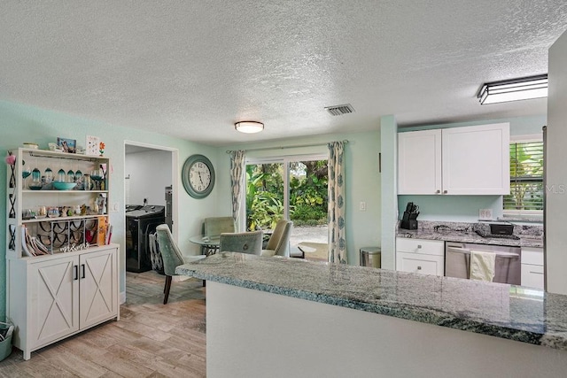 kitchen featuring dishwasher, white cabinets, light stone countertops, a textured ceiling, and light hardwood / wood-style flooring