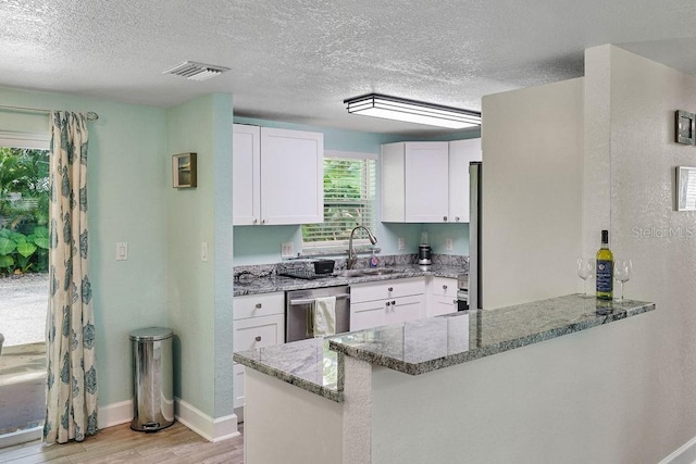 kitchen with stone counters, dishwasher, sink, white cabinets, and kitchen peninsula