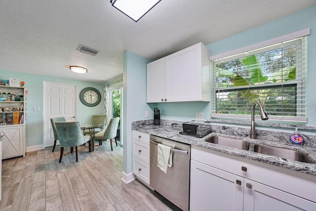 kitchen featuring sink, white cabinetry, light wood-type flooring, stainless steel dishwasher, and light stone countertops