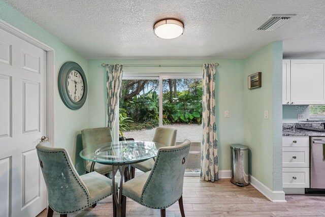 dining room with light hardwood / wood-style floors and a textured ceiling