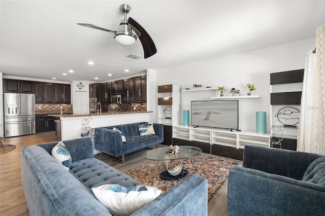 living room featuring sink, ceiling fan, and light hardwood / wood-style floors