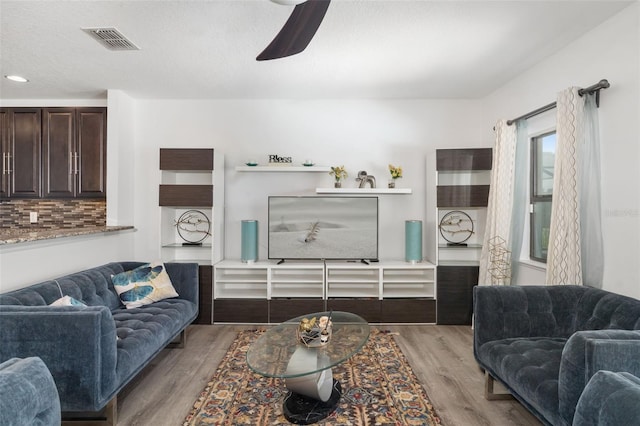 living room featuring ceiling fan, light hardwood / wood-style floors, and a textured ceiling