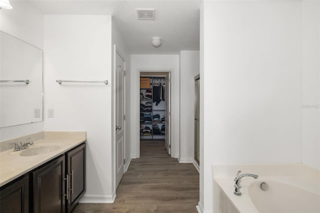 bathroom featuring plus walk in shower, hardwood / wood-style floors, a textured ceiling, and vanity