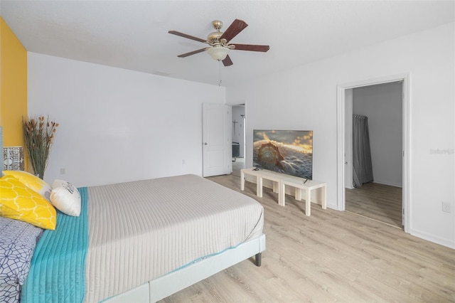 bedroom with light wood-type flooring, a spacious closet, ceiling fan, and a closet