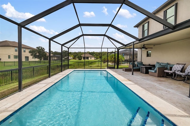 view of pool with a patio area, a lawn, outdoor lounge area, glass enclosure, and ceiling fan