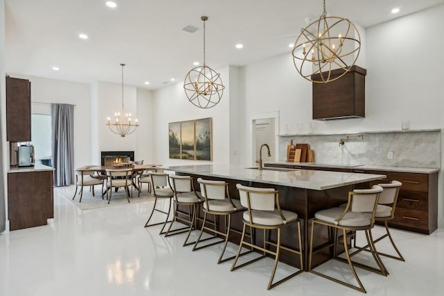 kitchen with pendant lighting, a kitchen breakfast bar, an inviting chandelier, sink, and a large island