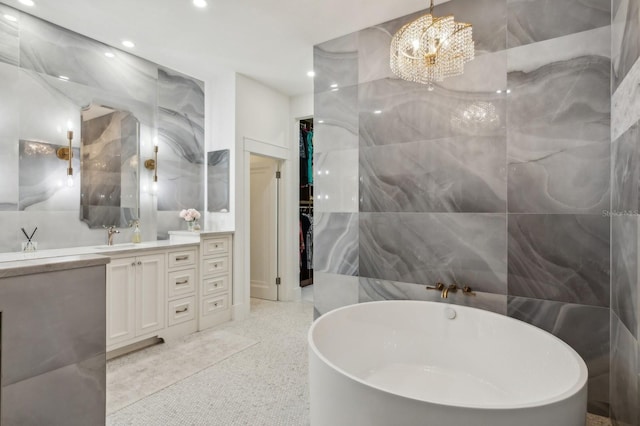 bathroom with vanity, a bath, a chandelier, and tile walls