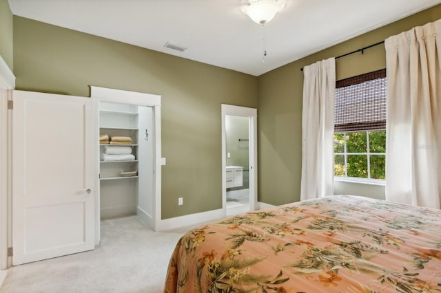 bedroom featuring a walk in closet, light colored carpet, and connected bathroom