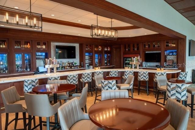 bar with pendant lighting, an inviting chandelier, and light hardwood / wood-style flooring