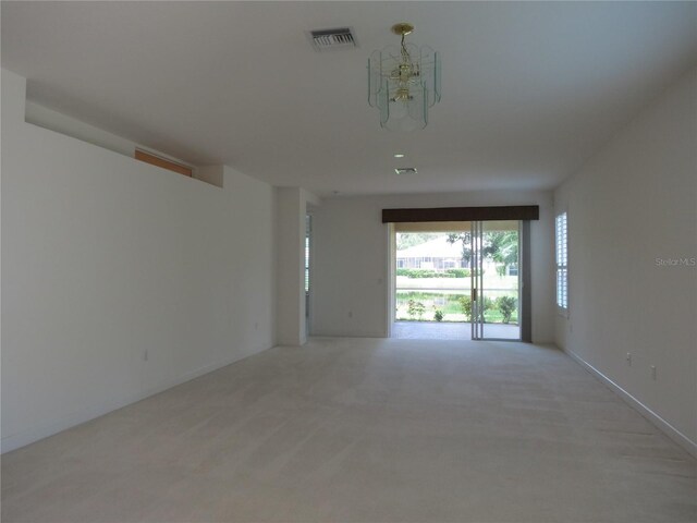 empty room with a chandelier and light colored carpet