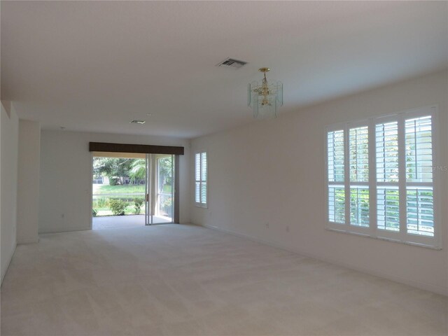 carpeted empty room featuring a chandelier