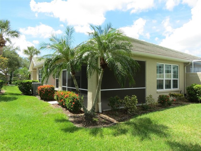 view of side of home with cooling unit, a lawn, and a sunroom