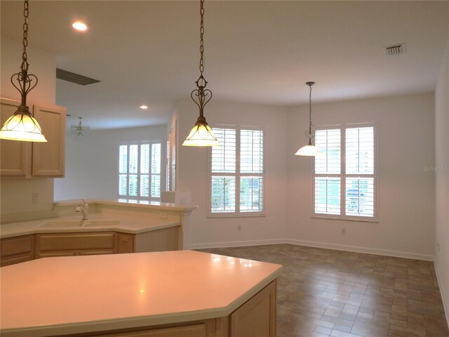 kitchen with plenty of natural light, light brown cabinetry, sink, and a kitchen island