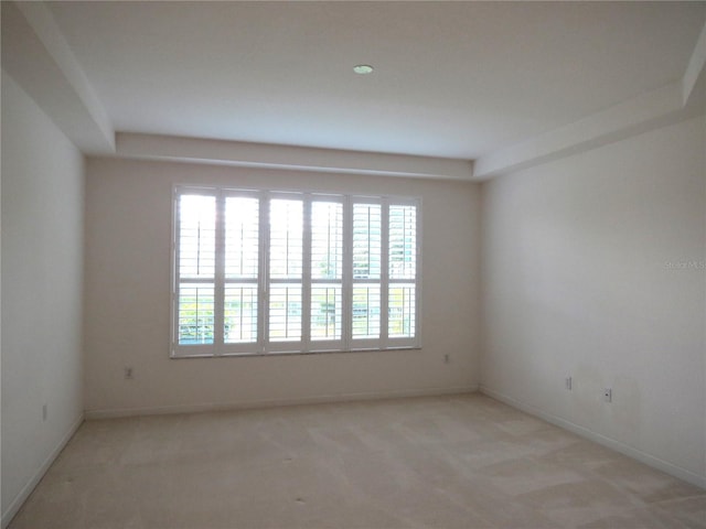 empty room featuring light colored carpet and baseboards