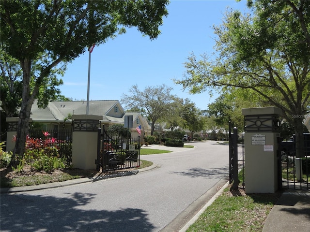 view of street with a gate, curbs, and a gated entry