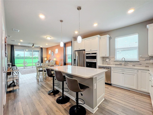 kitchen featuring appliances with stainless steel finishes, a center island, sink, and white cabinets