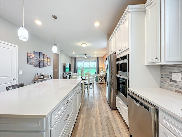 kitchen with appliances with stainless steel finishes, white cabinetry, and pendant lighting