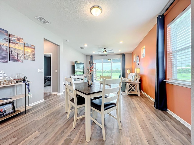 dining space featuring light hardwood / wood-style flooring, a textured ceiling, and ceiling fan