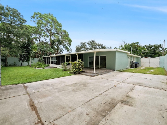 rear view of property featuring a sunroom, a lawn, and a carport