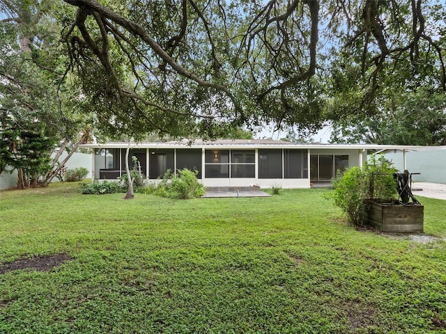 rear view of property featuring a yard and a sunroom