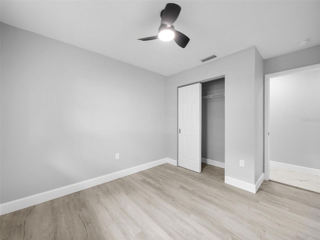 unfurnished bedroom with light wood-type flooring, ceiling fan, and a closet