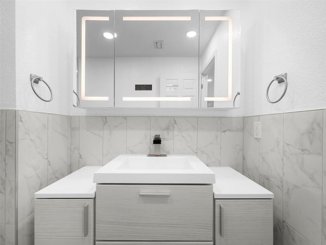 bathroom with vanity and tile walls