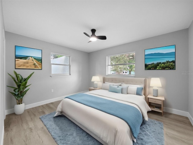 bedroom featuring ceiling fan, light wood-type flooring, and multiple windows