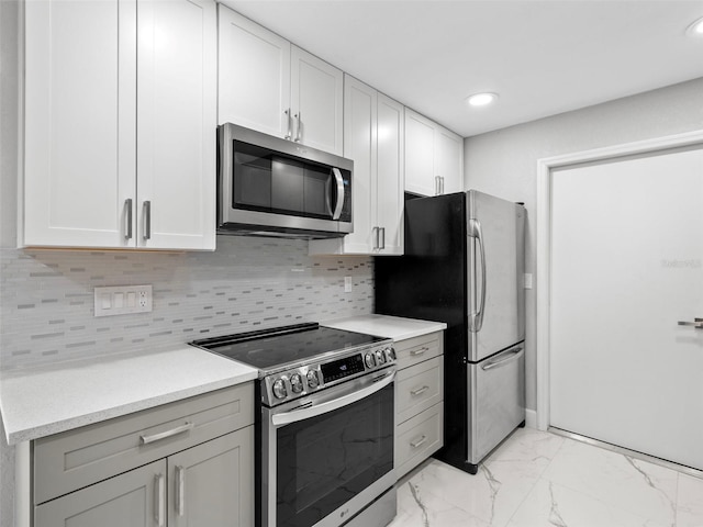 kitchen featuring white cabinets, stainless steel appliances, and tasteful backsplash