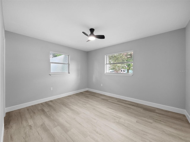 spare room with ceiling fan, a wealth of natural light, and light wood-type flooring