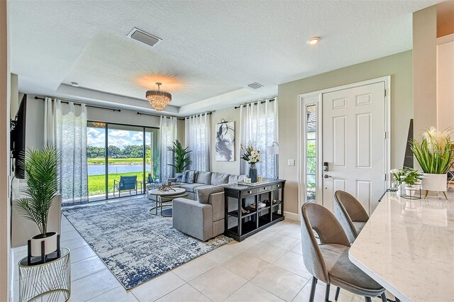 tiled living room with a wealth of natural light, a tray ceiling, and a textured ceiling