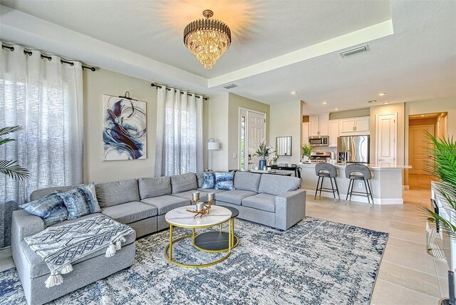 tiled living room featuring a textured ceiling and a chandelier