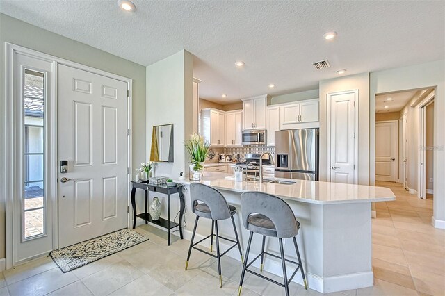 kitchen with sink, kitchen peninsula, white cabinetry, appliances with stainless steel finishes, and decorative backsplash