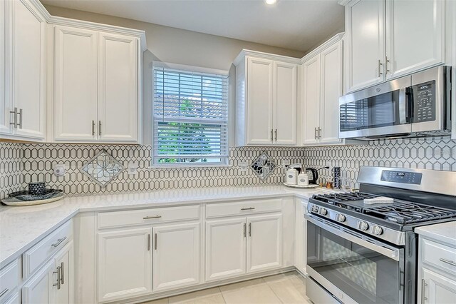 kitchen with decorative backsplash, white cabinetry, light stone countertops, light tile patterned floors, and stainless steel appliances