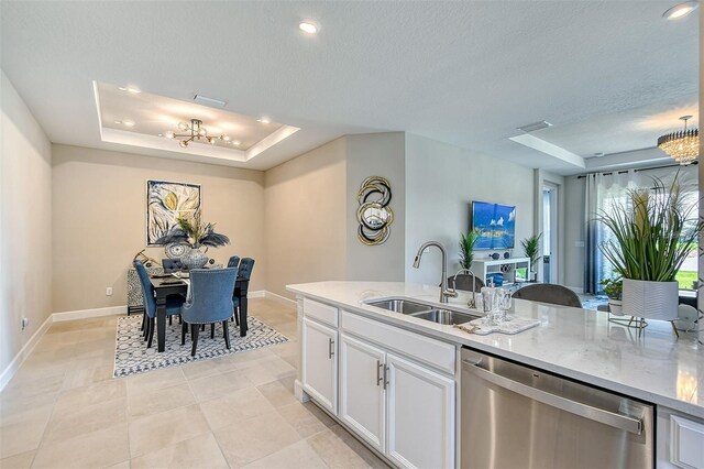 kitchen with a raised ceiling, sink, stainless steel dishwasher, a chandelier, and white cabinetry